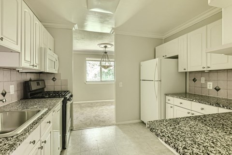 a kitchen with white cabinets and granite counter tops