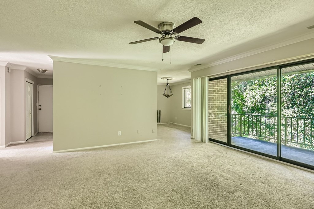 an empty living room with a ceiling fan and a large window