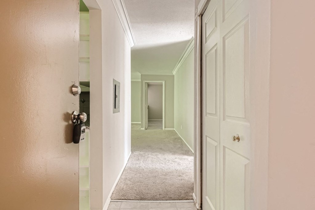 the hallway of a home with a door open to a hallway with a white door