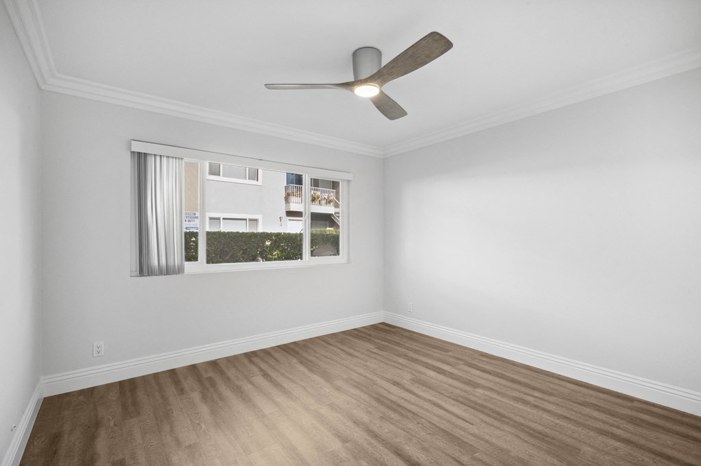 an empty room with a window and a ceiling fan