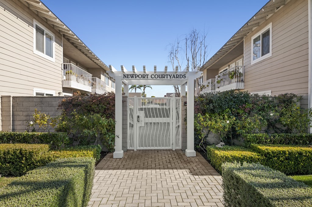 the gate to the backyard courtyard of a home with a white gate