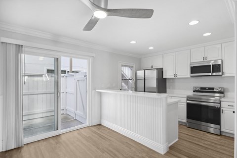 a white kitchen with a large island and a door to a refrigerator