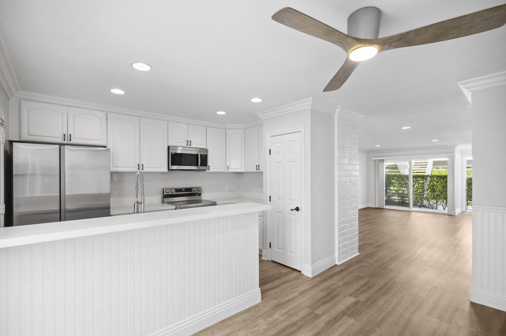 a white kitchen with a large island and a ceiling fan