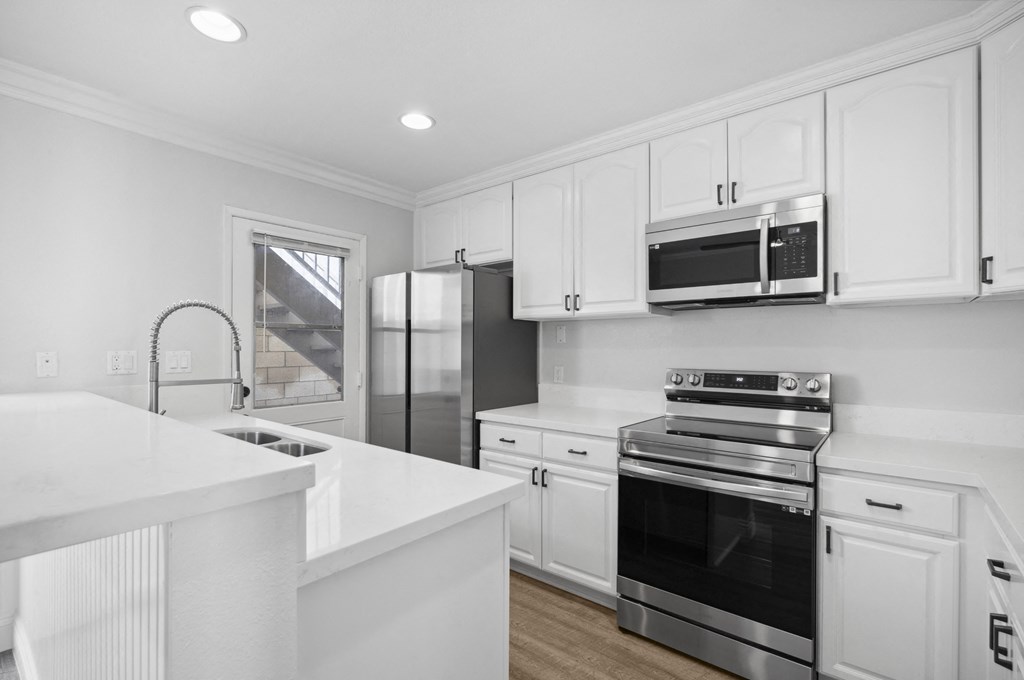a white kitchen with white cabinets and stainless steel appliances