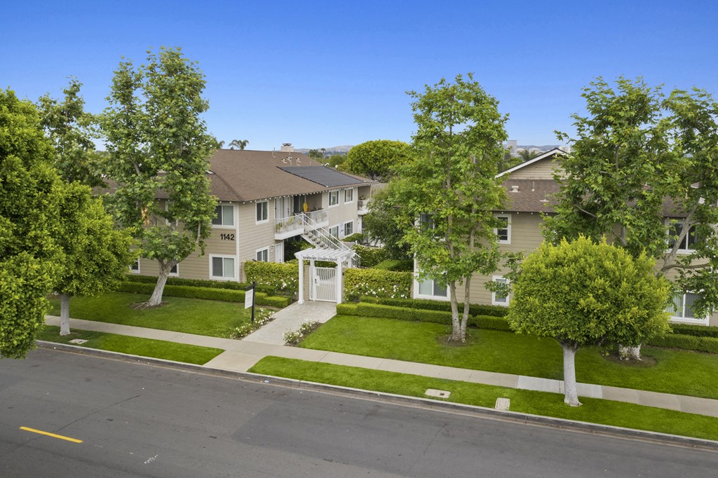 an aerial view of an apartment complex with green lawns and trees
