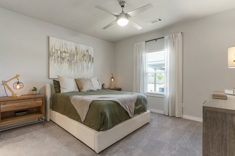 A bedroom with a large bed and a ceiling fan.