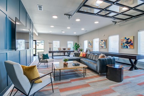 A modern living room with a grey sofa, a yellow cushion, a wooden coffee table, and a large painting on the wall.