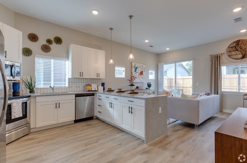 A kitchen with white cabinets and a wooden floor.