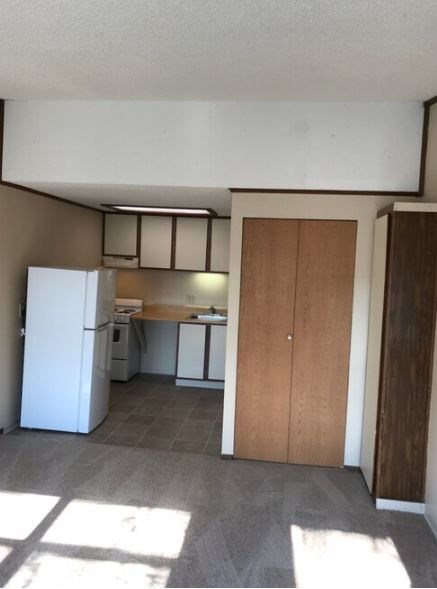 A kitchen with a white fridge and a wooden door.