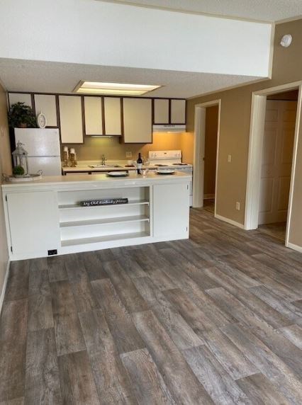 A kitchen with a white counter and wooden flooring.