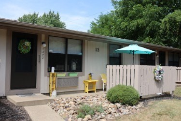A house with a green umbrella and a wreath on the door.