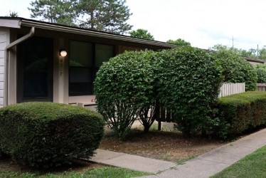 A house with a green hedge in front.