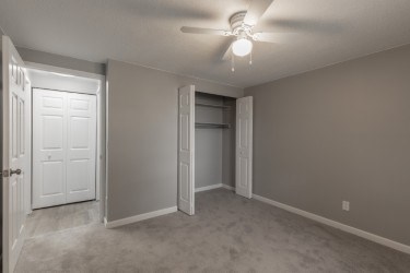 A room with a ceiling fan and a door.