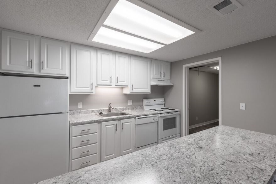 A kitchen with white cabinets and granite countertops.