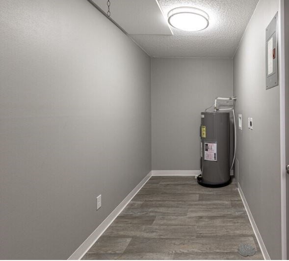 A room with a grey floor and a grey wall with a fridge in it.