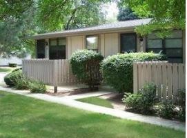 A house with a white fence and green bushes in front.