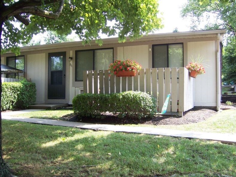 A small house with a white picket fence and hanging flower pots.