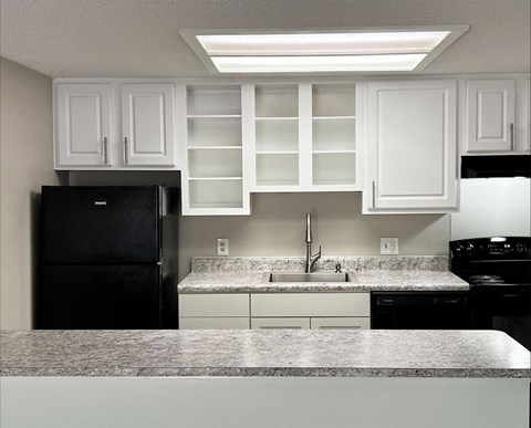 A kitchen with black appliances and white cabinets.