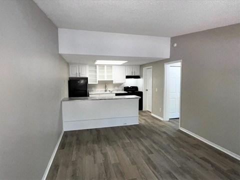 A kitchen with a black fridge, white cabinets, and a white island.
