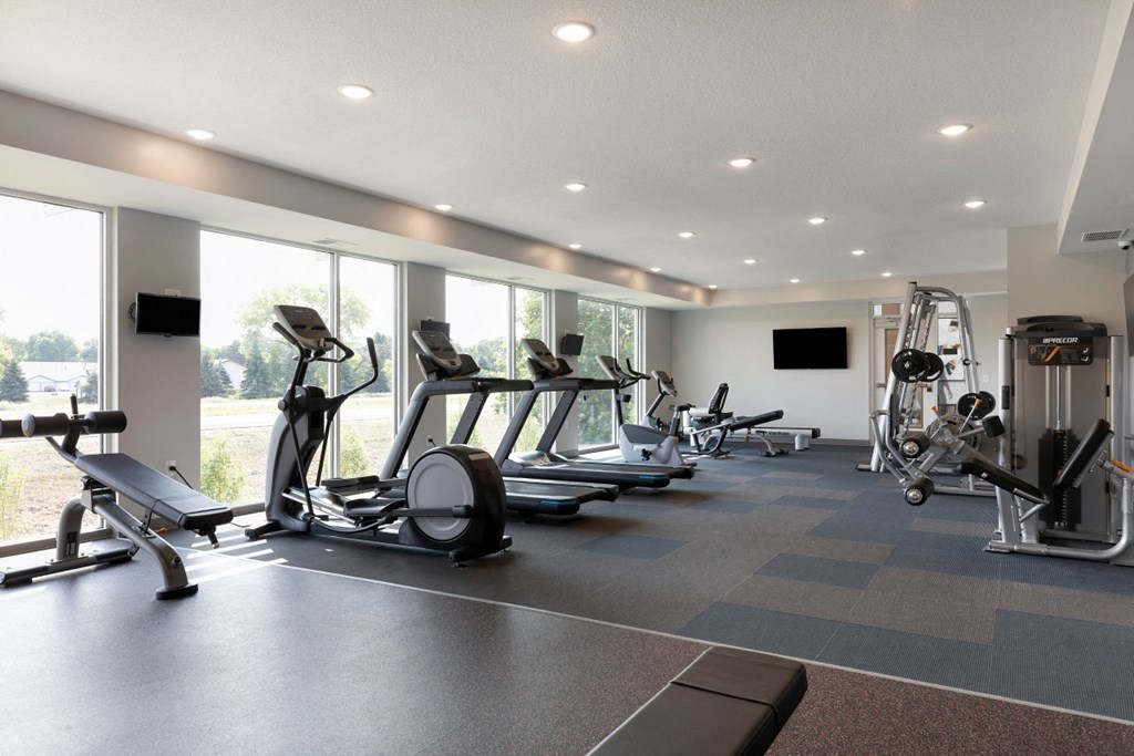 a gym with cardio equipment and windows in a building