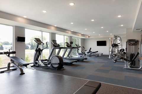 a gym with cardio equipment and windows in a building