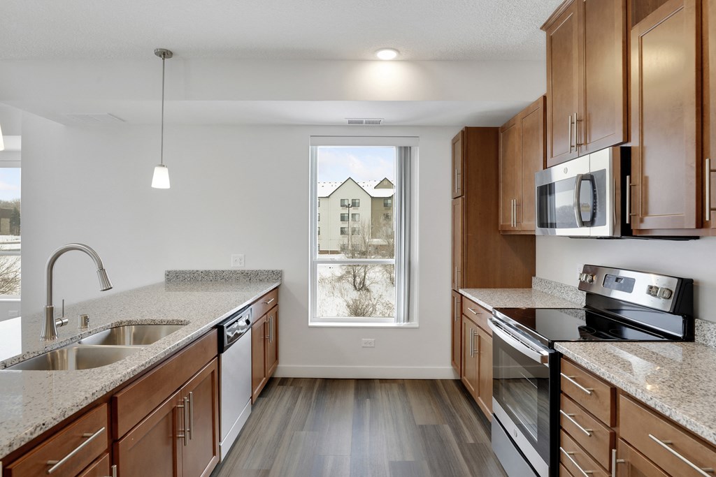 an empty kitchen with granite counter tops and wooden cabinets