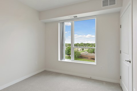 A room with a large window overlooking a residential area at Sonder Point 50+ Apartments, Brooklyn Center, 55430