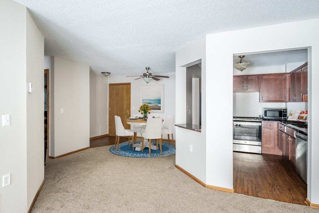 a dining area with a table and chairs and a kitchen in the background