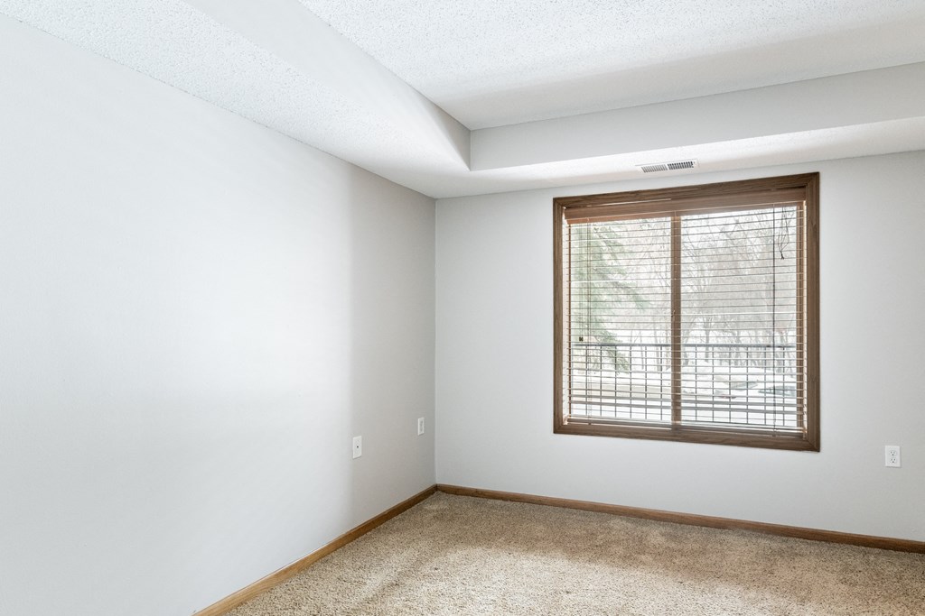 a bedroom with white walls and a large window