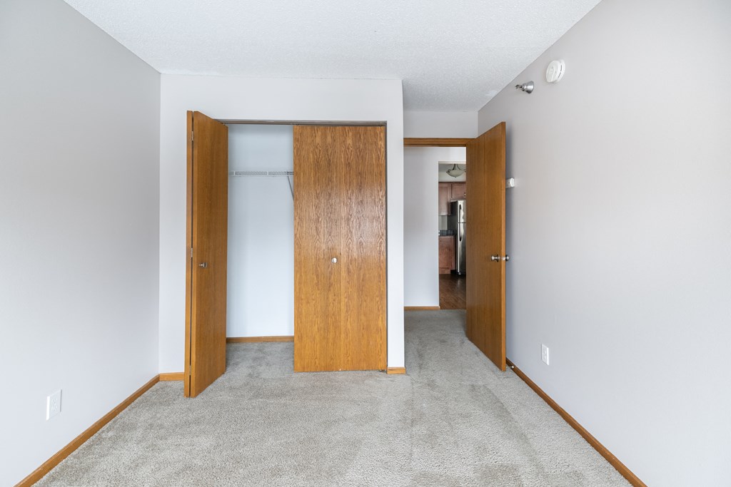 an open door leads into an empty room with a carpeted floor