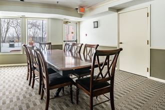 a large wooden table with chairs in a room with a large window