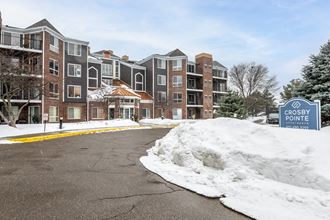 a parking lot with snow on the ground and an apartment building in the background