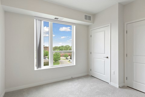 A room with a large window overlooking a residential area at Sonder Point 50+ Apartments, Brooklyn Center, MN