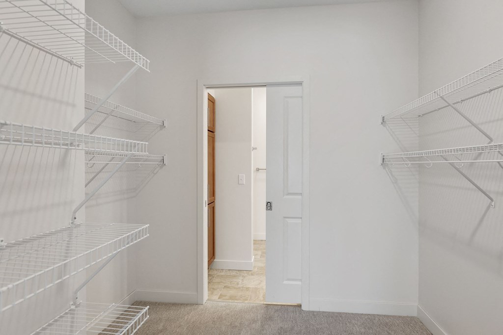 a white closet with empty shelves and a door to a bathroom