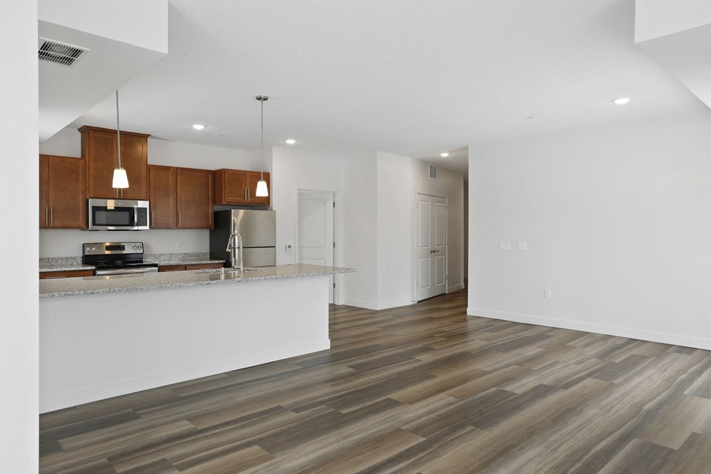 an empty living room with a kitchen with a counter top