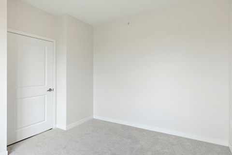 A white door is on the left of a room with white walls and carpeted floor at Sonder Point 50+ Apartments, Minnesota, 55430