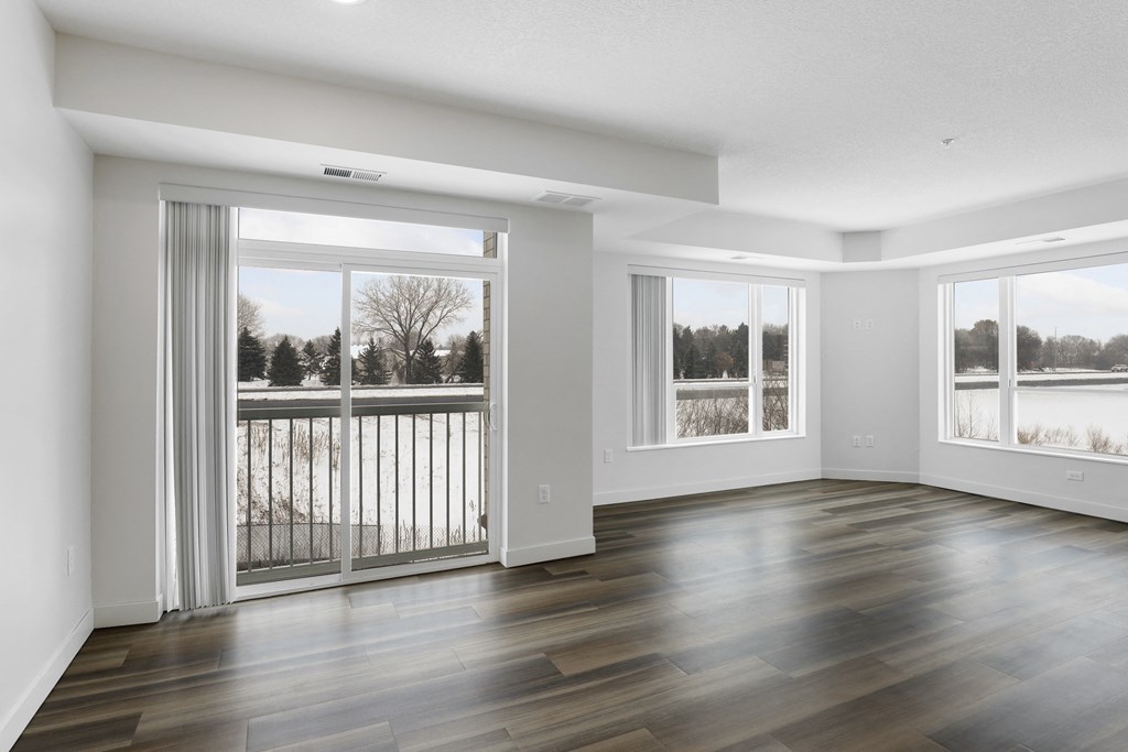 the living room of an empty house with wood floors and a balcony