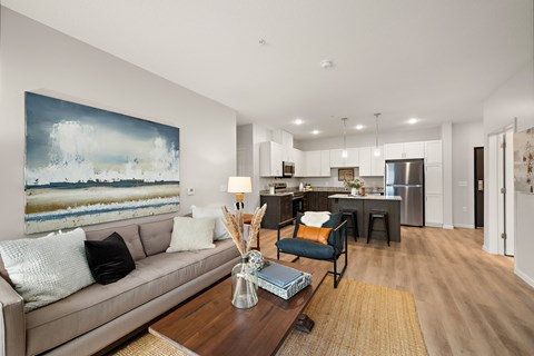 A modern living room with a large painting on the wall and a beige sofa.