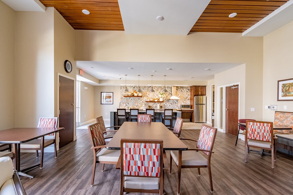 a dining area with a table and chairs and a kitchen in the background