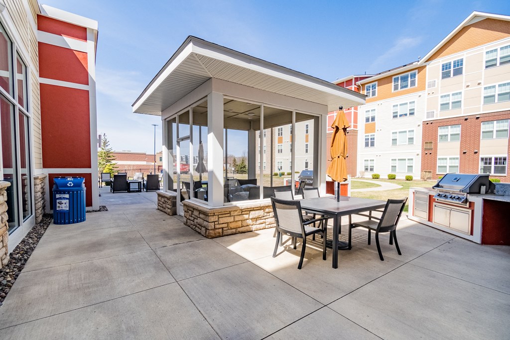 a covered patio with a grill and dining table