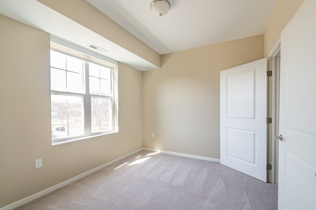 an empty bedroom with a large window and a white door