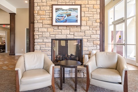 a living room with two white chairs and a fireplace