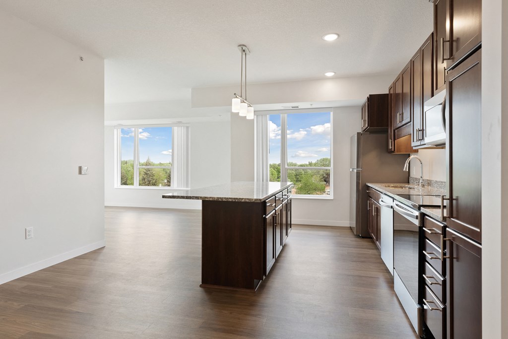 A modern kitchen with dark wood cabinets and a central island at Sonder Point 50+ Apartments, Brooklyn Center