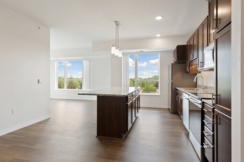 A modern kitchen with dark wood cabinets and a central island at Sonder Point 50+ Apartments, Brooklyn Center