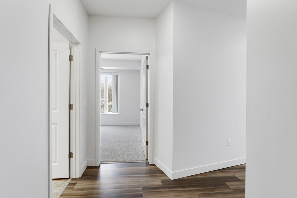 an empty hallway with white walls and wood flooring
