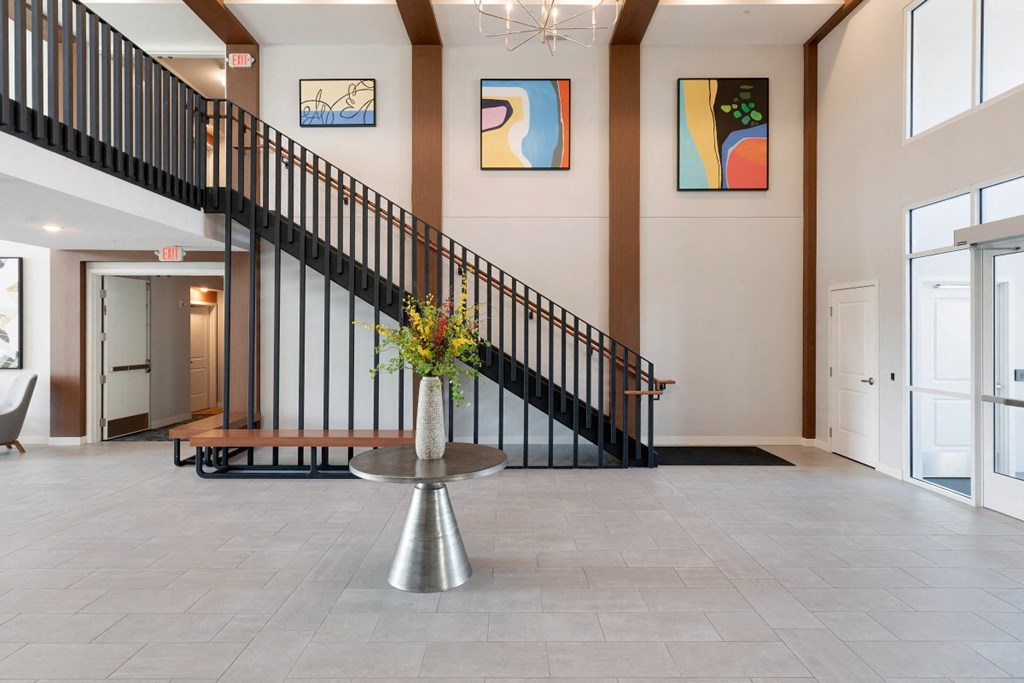 a lobby with a staircase and a vase with flowers
