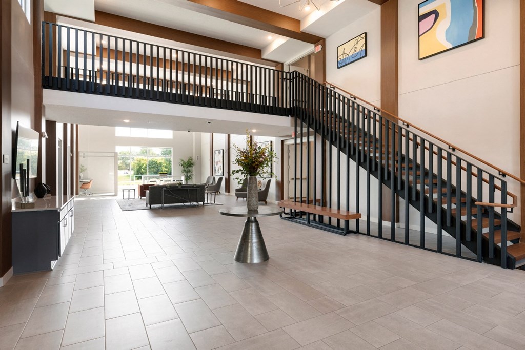 the lobby of a hotel with a staircase and a lobby area with a seating area