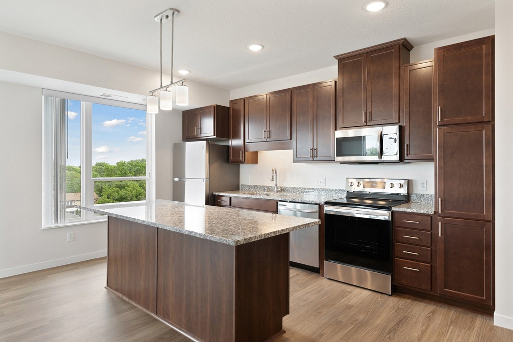 A kitchen with brown cabinets and a granite countertop at Sonder Point 50+ Apartments, Minnesota