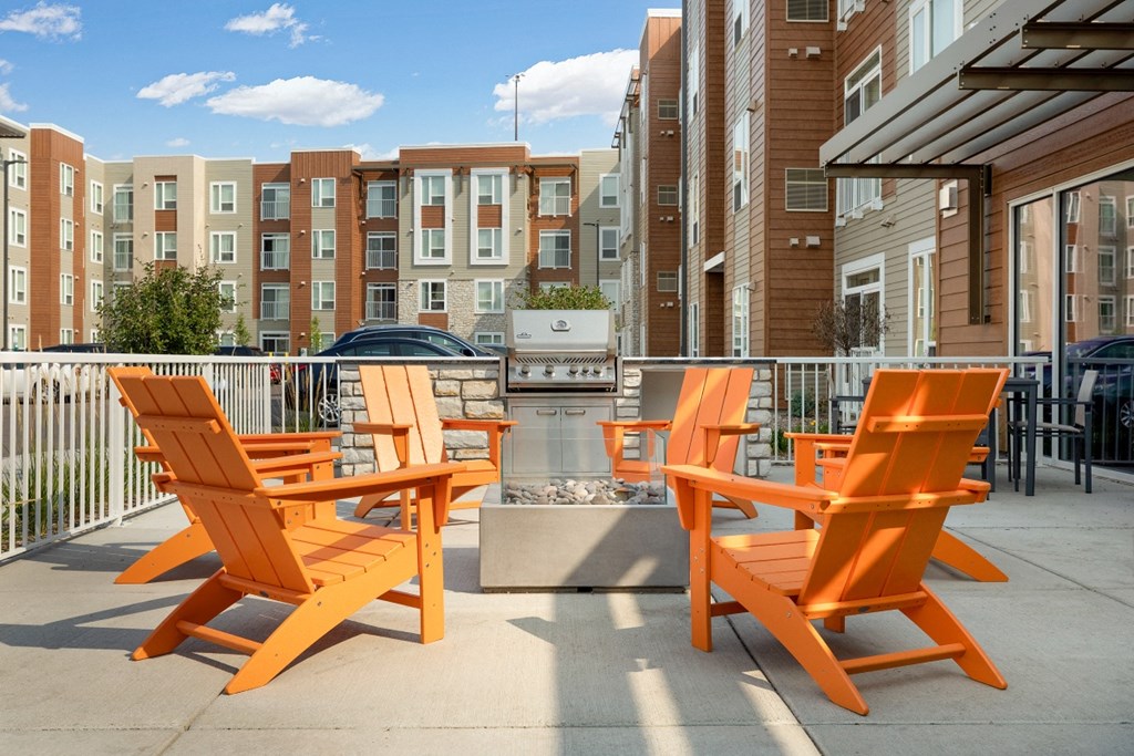 an apartment patio with orange chairs and a grill