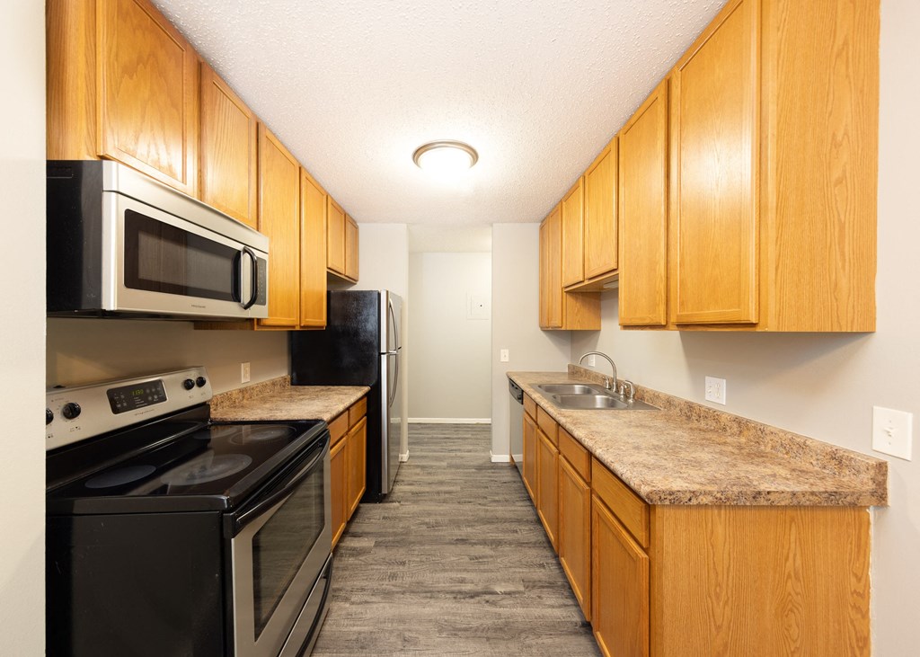 a kitchen with wood cabinets and black appliances and granite counter tops